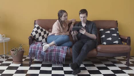 young couple watching tablet on sofa