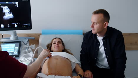 smiling caucasian couple having ultrasonic check up. happy future parents look attentively on the equipment screen.