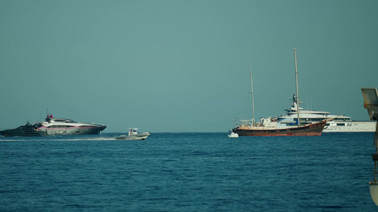 Yacht di lusso e una barca tradizionale che navigano in acque blu calme sotto un cielo sereno, a rappresentare viaggi e turismo.