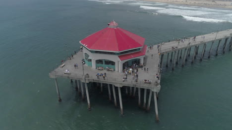 aerial - rotating drone shot of red building at end of ocean pier