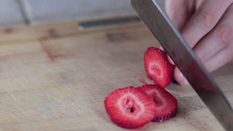 Slow-motion-tight-shot-of-a-sharp-knife-cutting-into-a-juicy-strawberry-for-a-healthy-snack