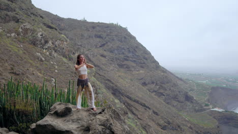 contra el sereno telón de fondo del océano azul al atardecer, una mujer joven practica yoga en una orilla rocosa, retratando los conceptos de un estilo de vida saludable, armonía y la unidad del hombre y la naturaleza