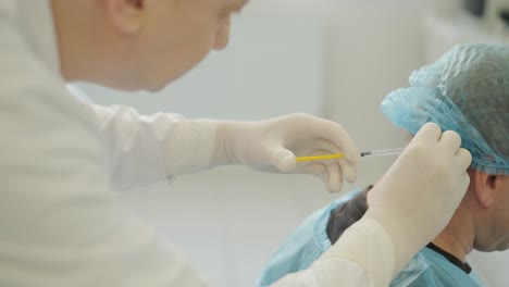 un médico que administra inyecciones de botulino a un paciente como tratamiento para el bruxismo y la espasticidad. el entorno clínico hace hincapié en la profesionalidad y la experiencia médica