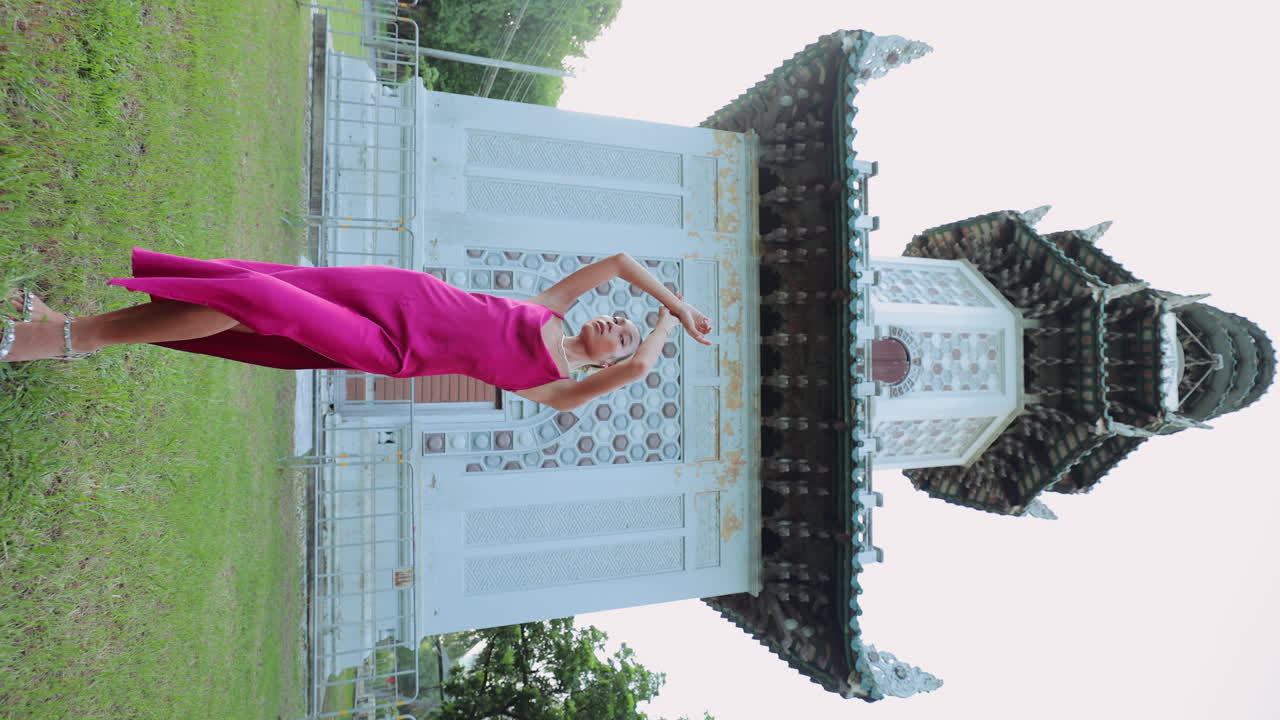 Graceful Woman in Pink Dress Posing by an Ornate Temple-like Building