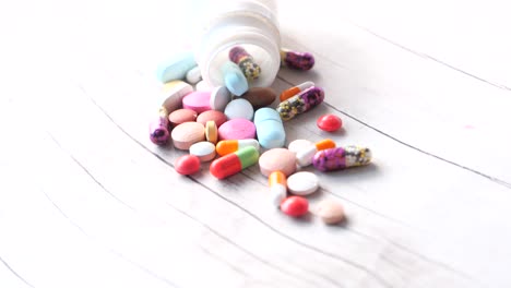 assorted pills and capsules on a white wooden surface