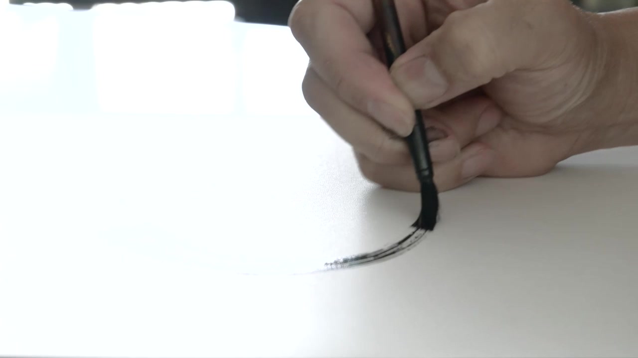 Primo piano sulla mano che inizia un tratto di calligrafia tradizionale in stile orientale
