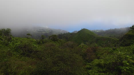 Plataforma-Rodante-Aérea-Sobre-Una-Exuberante-Selva-Tropical-Con-Colinas-Y-Picos,-Nubes-Bajas-Cuelgan-Sobre-El-Océano