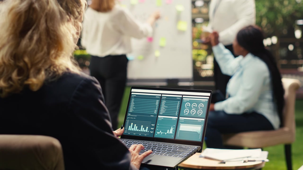 Businesswoman Analyzing Financial Data on Laptop During Team Meeting