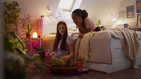 chicas adolescentes comiendo pizza y usando una computadora portátil en un dormitorio