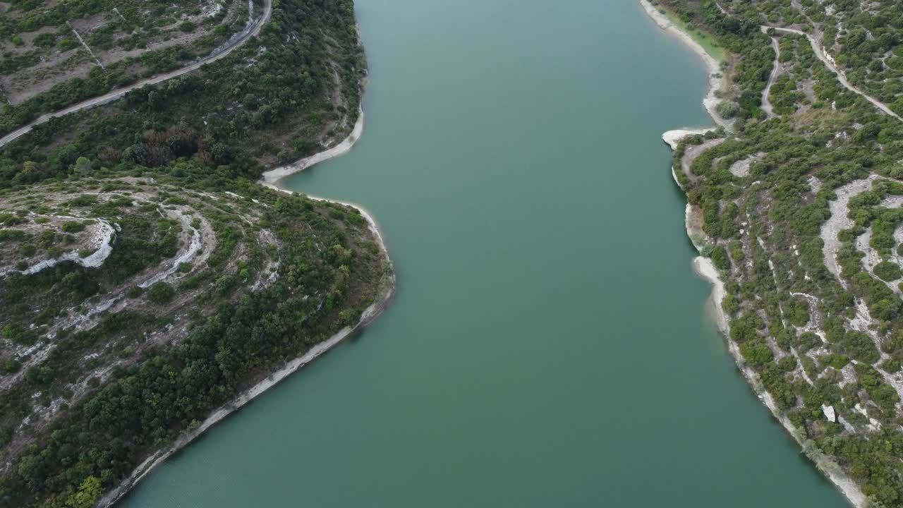 Aerial view of a calm, winding river cutting through lush terraced hills in the Douro Valley, Portugal. The region is known for its vineyards and scenic natural beauty