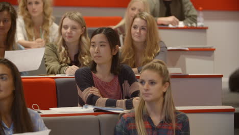 handheld tilt shot of students in university lecture theatre