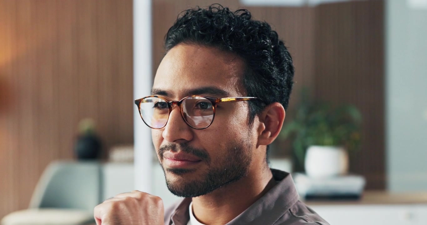 Thoughtful Young Man Wearing Glasses in a Modern Office