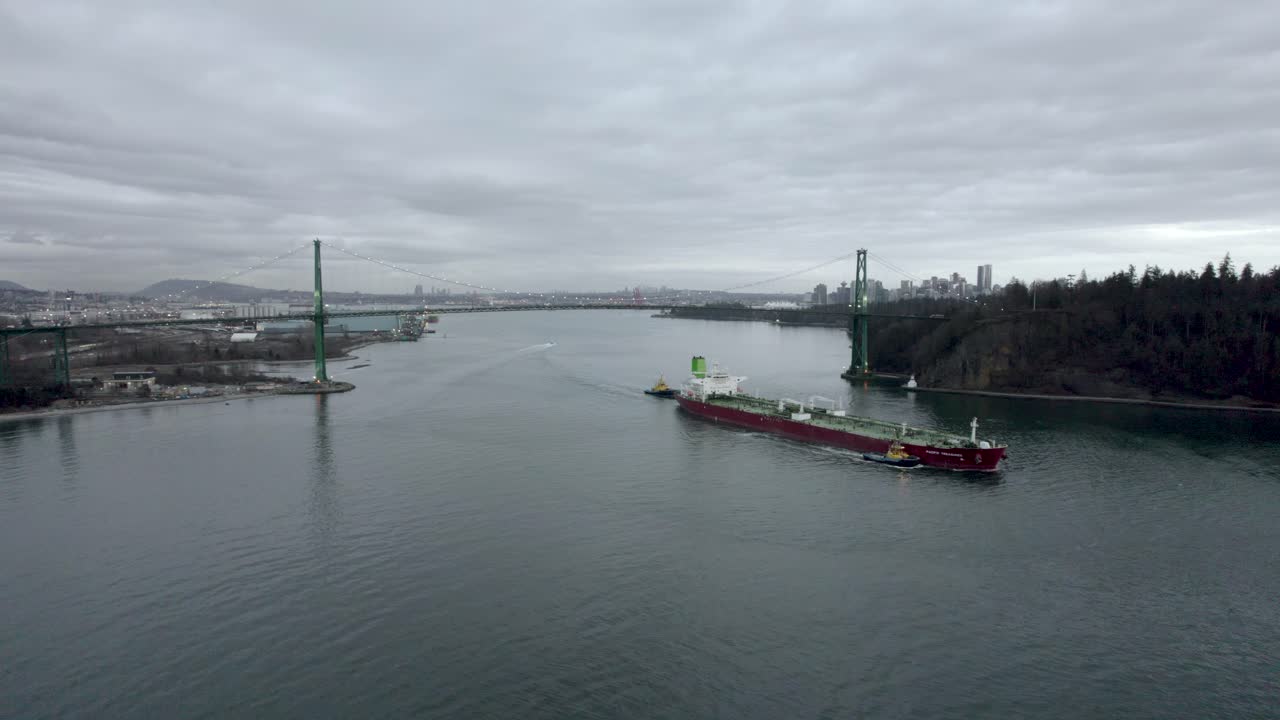 캐나다 밴쿠버를 배경으로 라이온스 게이트 다리 아래를 지나가는 붉은 바지선