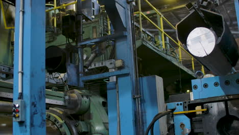 An automated machine at a factory, picking a metal rod with a clamp and transporting it to a conveyor