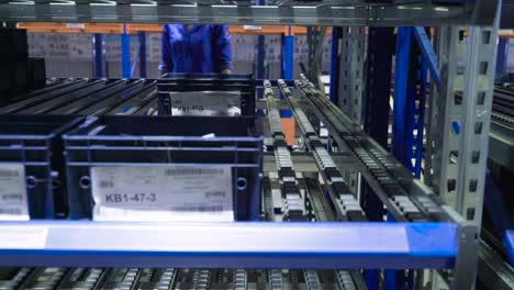 trabajador que maneja piezas en un sistema de almacén automatizado