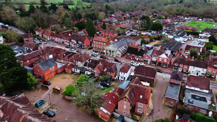 Ripresa aerea panoramica con drone sulla periferia di Southampton con le abitazioni del villaggio di Botley al tramonto in una nuvolosa e coperta giornata invernale, con auto che passano sulle strade sottostanti oltre le piccole case del paese.