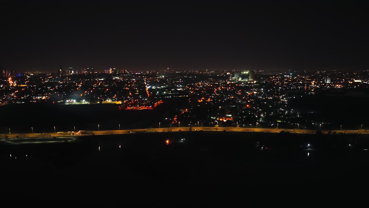 A sweeping aerial nightscape of Asuncion, Paraguay showcasing the illuminated city skyline and Costanera avenue from Heroes of Chaco bridge under a starry sky, captured in high definition