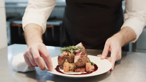 Caucasian-male-chef-cleaning-plate-with-prepared-meal-in-kitchen,-slow-motion