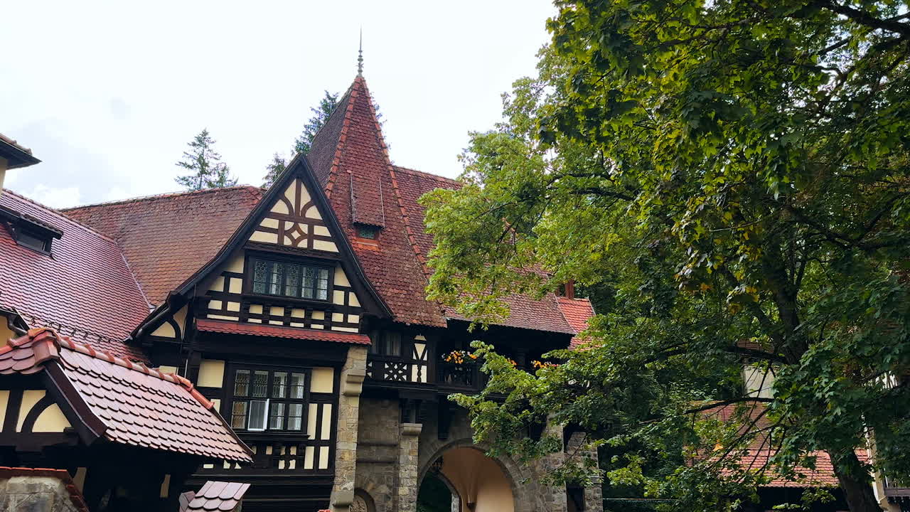 Sinaia, Romania, 17 July 2025: Old-style building with beautiful tiled roof. Green trees grow around. Peles Castle in Sinaia, the Carpathians, Romania