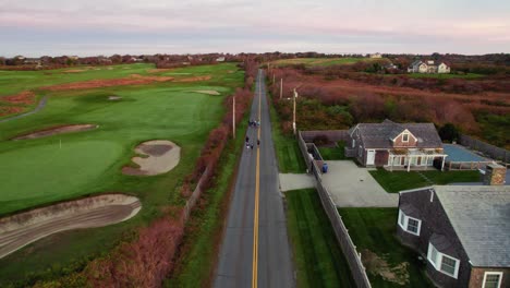 Aerial-of-runners-running-on-a-long-road-next-to-a-golf-course-at-sunrise-training-for-a-10k-race