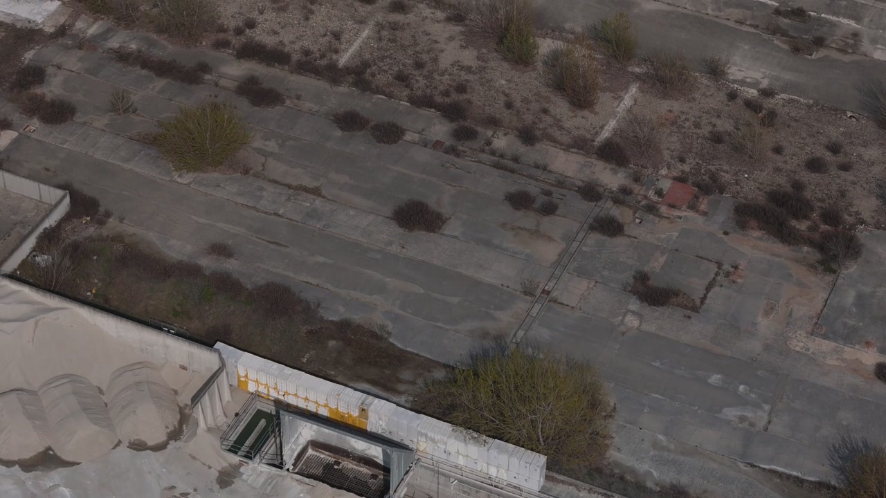Tilt Up Over Abandoned Industrial Complex With Crumbling Concrete and Dry Weeds Portraying the Silent Decay of Forgotten Industrial Infrastructure
