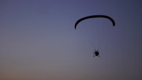 the pilot on a paraglider flies from the camera gradually moving away into the distance against the sunset beautiful sky. beautiful background background picture. concept of freedom