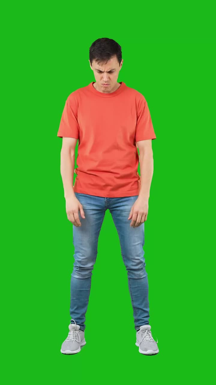 Angry man with crossed arms standing against a green screen