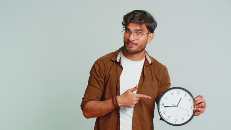 jeune homme indien montrant l'heure sur le mur horloge de bureau, ok, pouce haut, approuver, dépêchez-vous, date limite