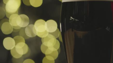 close up of pint of irish stout in glass to celebrate st patricks day against abstract lights