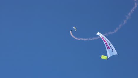 skydivers with colorful parachutes carrying advertisement banners