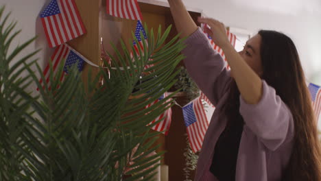 woman at home hanging up american stars and stripes flag bunting for party celebrating 4th july independence day 5