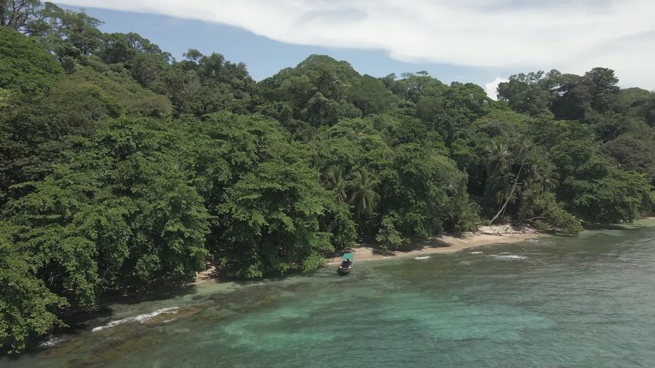Lone boat tied ashore, dense jungle forest at remote Costa Rica beach