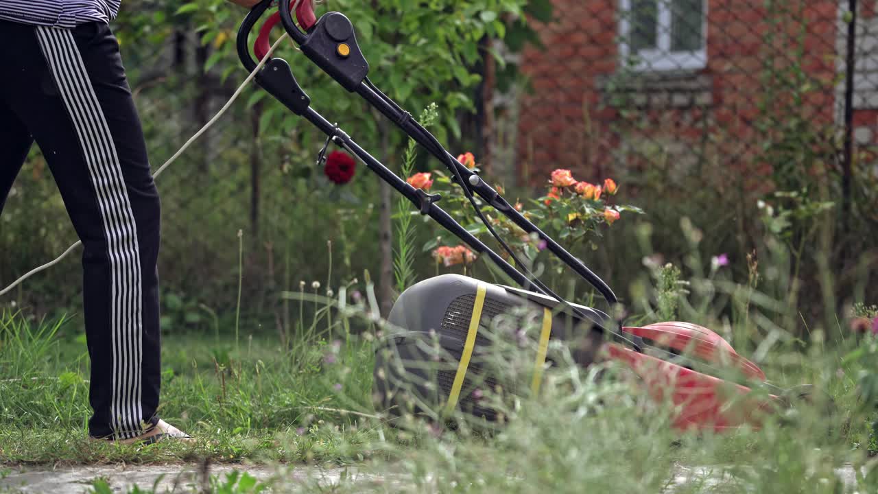 Red lawn mower in the garden. Mowing lawns.