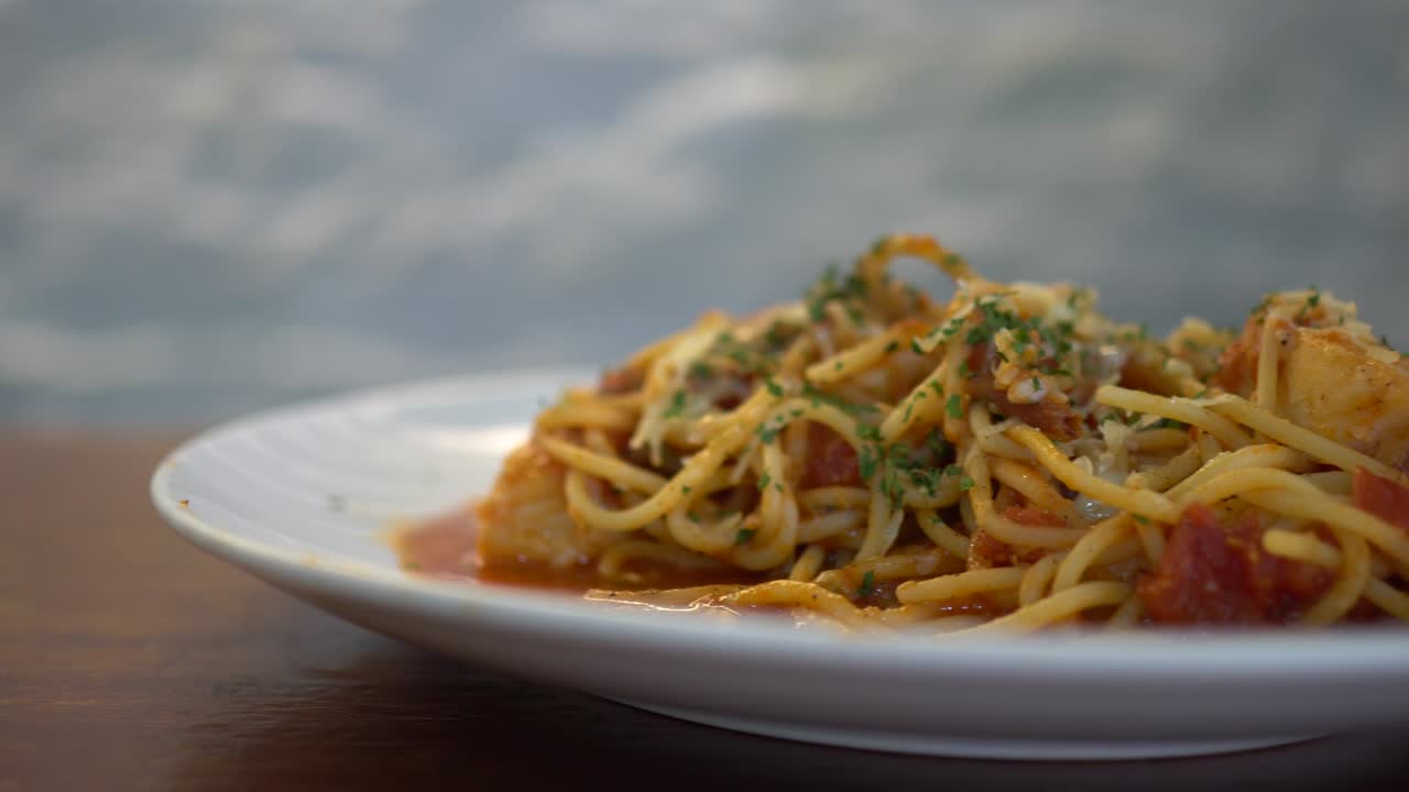 A little girl eats tomato seafood spaghetti in a restaurant. Truck shot from right to left.