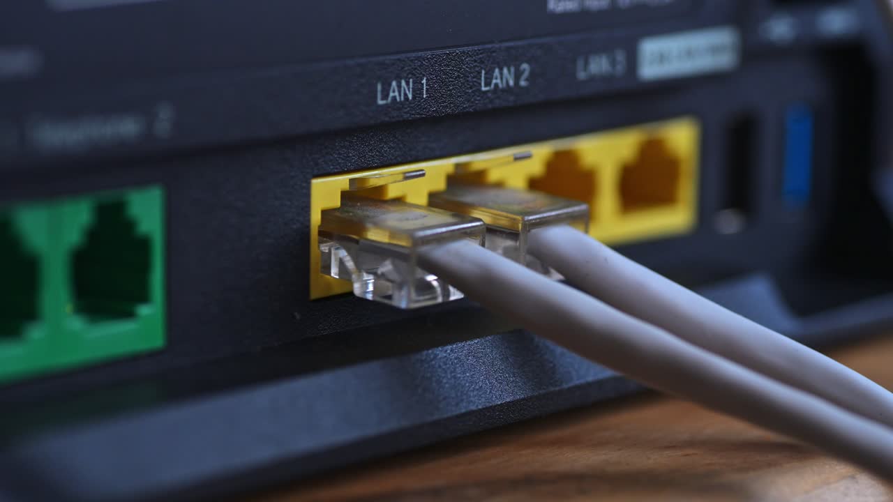 Close-up view of an Ethernet cable being plugged into a yellow LAN port of a router. The video highlights the network connection setup in a home or office environment