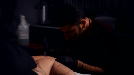 joven artista del tatuaje hipster haciendo tatuaje en la pierna del hombre