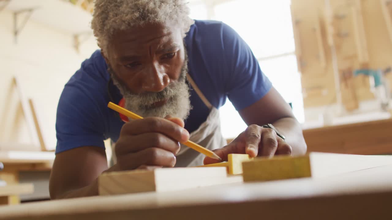 carpintero afroamericano haciendo marcas de lápiz en una tabla de madera