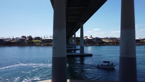 Aerial-tracking-left-to-right-of-fishing-boat-passing-under-bridge