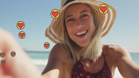 animación de iconos en forma de corazón, hermosa mujer caucásica sosteniendo una cámara y grabando en la playa
