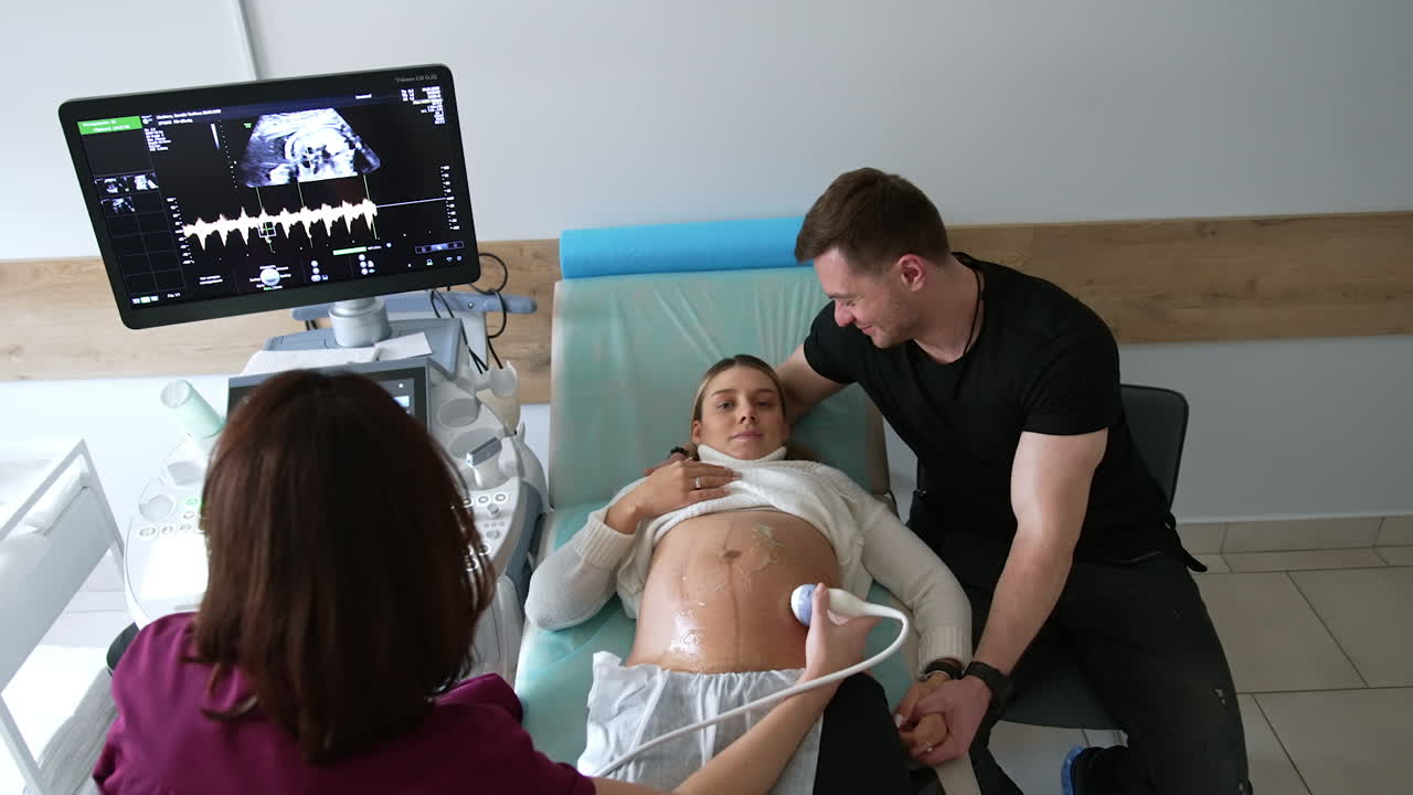 Pregnant woman undergoing ultrasound scan with her partner