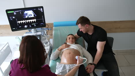 pregnant woman undergoing ultrasound scan with her partner