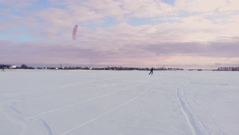 a male athlete in sports outfit is doing snow kiting on beautiful winter landscape.