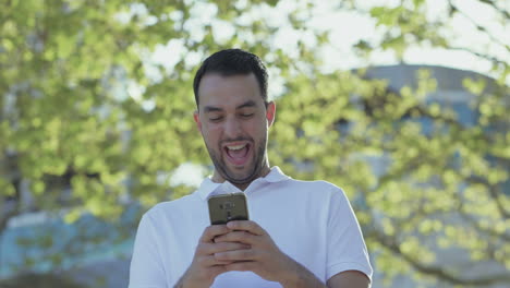 young bearded man holding smartphone and laughing.