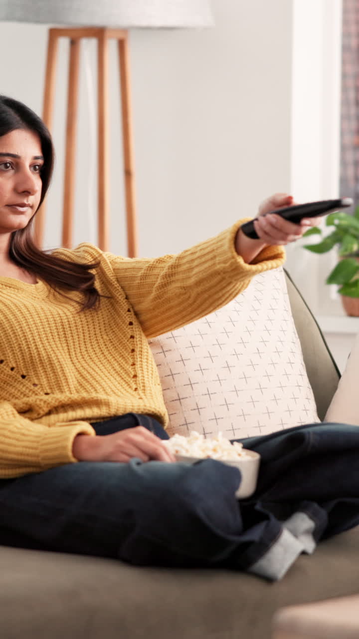Kvinde slapper af på sofaen med popcorn
