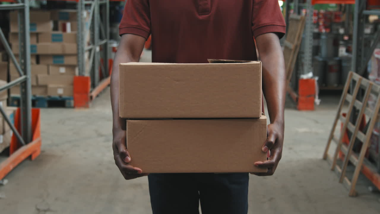 Unrecognizable Man Carrying Boxes in Warehouse