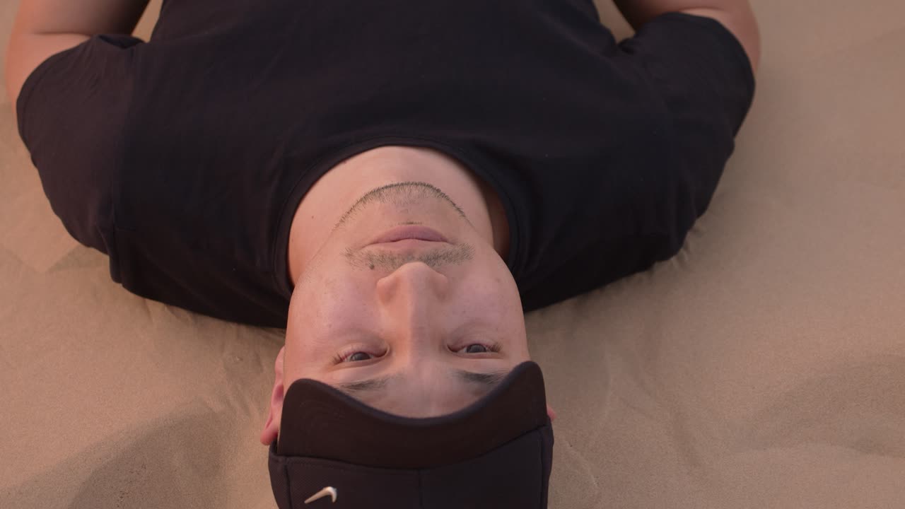 하늘을 바라보며 사막에 누워 있는 청년