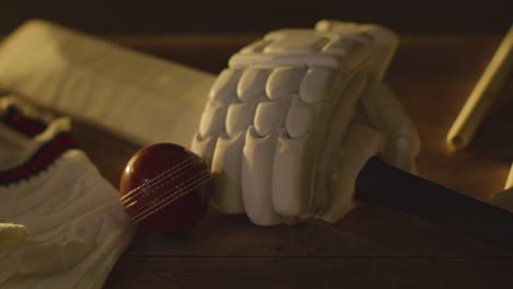 cricket stilleven met close-up van bat ball handschoenen stumps jumper en bails liggen op houten oppervlak in kleedkamer 2