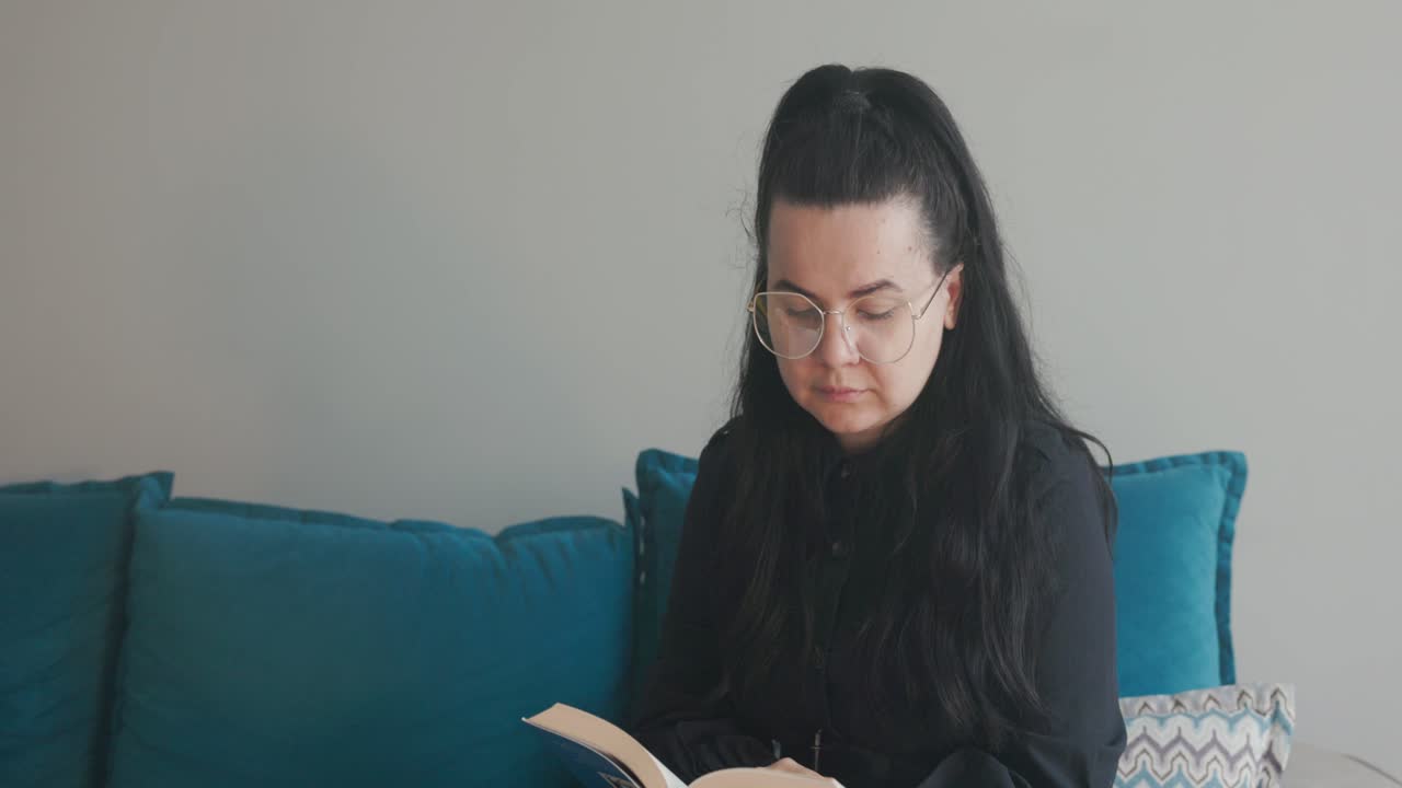 Woman In Living Room Looks Around, Distracted While Reading Book In House