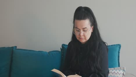 mujer en la sala de estar mira a su alrededor, distraída mientras lee un libro en la casa