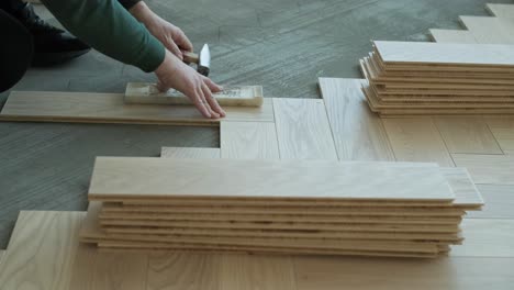 worker installing wooden flooring with hammer and tapping block